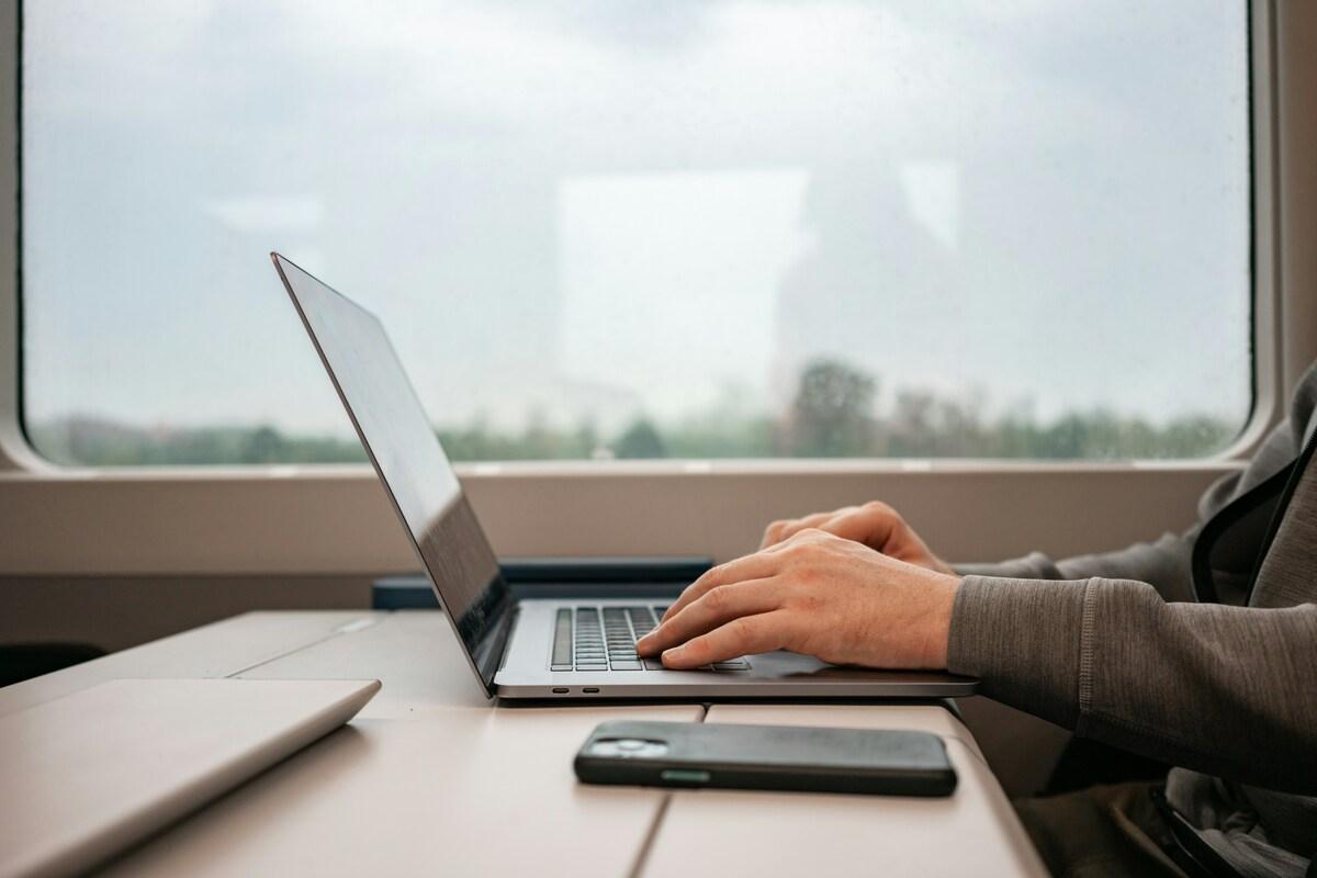 Ein Mann arbeitet während seiner Geschäftsreise mit Lanes & Planes an seinem Laptop im Zug.