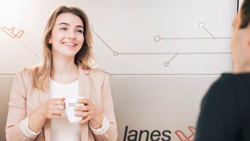 Lächelnde Mitarbeiterin mit Lanes & Planes Tasse